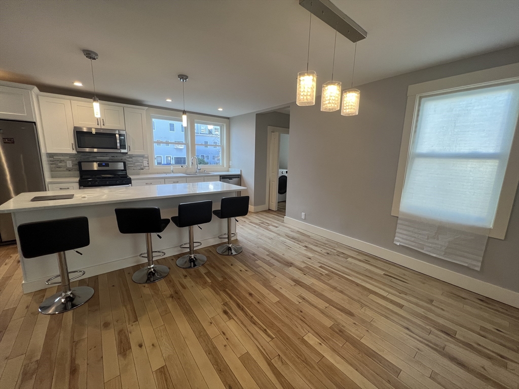 39 Snow Street, Unit 1 Boston, MA 02135 - Photo 23 of 35 a view of a kitchen with kitchen island stainless steel appliances wooden floor dining table and chairs