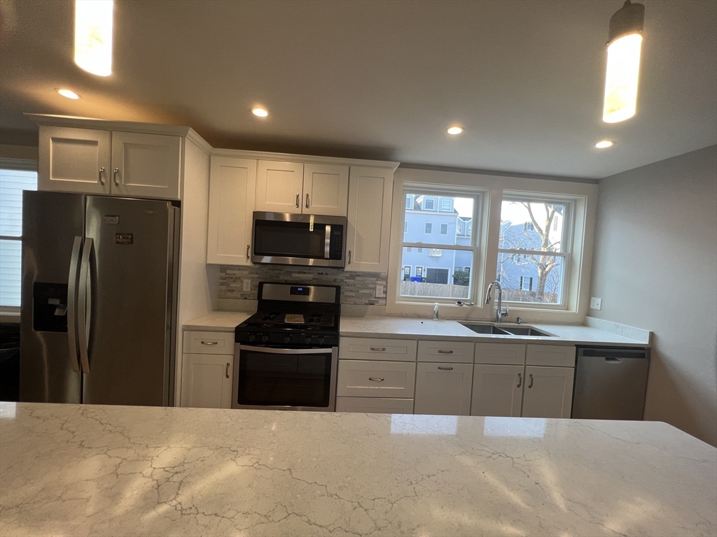 39 Snow Street, Unit 1 Boston, MA 02135 - Photo 3 of 35 a kitchen with stainless steel appliances granite countertop a refrigerator and a sink