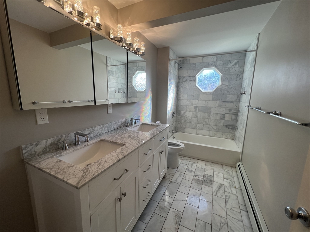 39 Snow Street, Unit 1 Boston, MA 02135 - Photo 34 of 35 a bathroom with a granite countertop sink a mirror and a bathtub