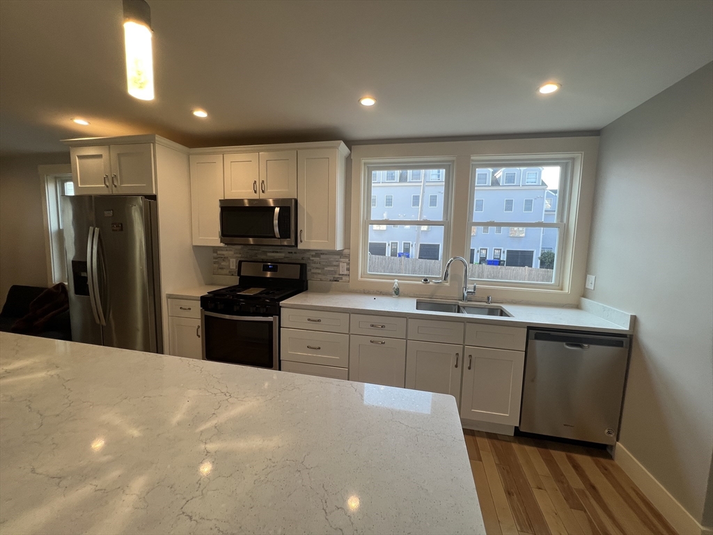 39 Snow Street, Unit 1 Boston, MA 02135 - Photo 4 of 35 a kitchen with granite countertop a refrigerator stove top oven and sink