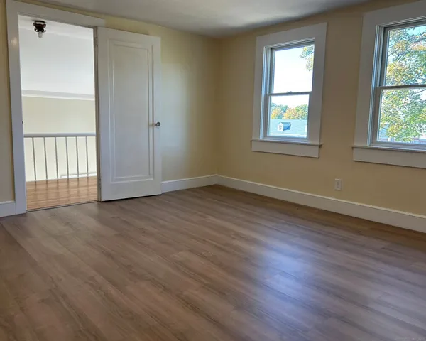 an empty room with wooden floor and windows