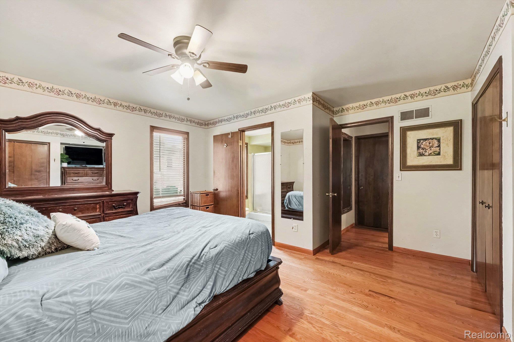 107 Michelle Drive Romeo, MI 48065 - Photo 16 of 30 Hardwood flooring throughout, featuring a ceiling fan with integrated lighting, window with blinds, and multiple solid panel doors