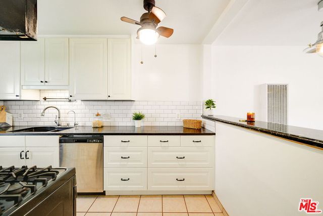a kitchen with granite countertop white cabinets and stainless steel appliances