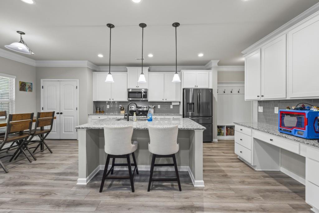 660 Country Ridge Drive Hoschton, GA 30548 - Photo 14 of 58 a kitchen with stainless steel appliances kitchen island granite countertop a dining table chairs and sink