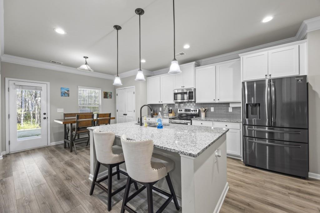 660 Country Ridge Drive Hoschton, GA 30548 - Photo 16 of 58 a kitchen with stainless steel appliances granite countertop a stove a refrigerator a kitchen island a dining table and chairs with wooden floor