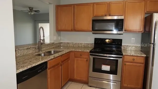 a kitchen with granite countertop a sink stove and microwave
