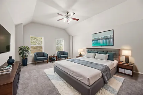 a spacious bedroom with a bed a couch and a flat screen tv