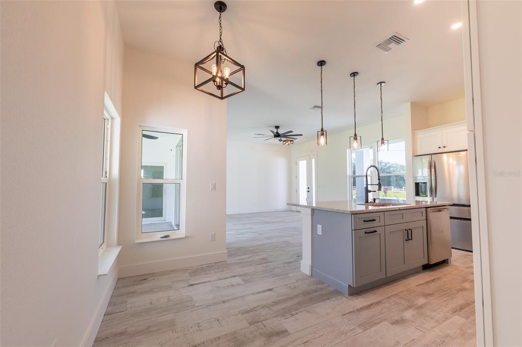 8846 Southwest Liverpool Road Arcadia, FL 34269 - Photo 19 of 29 a large kitchen with stainless steel appliances kitchen island granite countertop a stove a sink and dishwasher a refrigerator with wooden floor