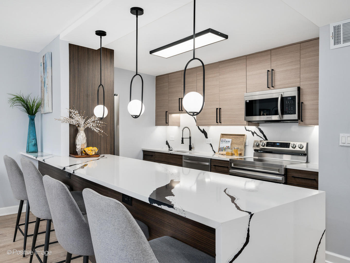 5455 North Sheridan Road, Unit 1511 Chicago, IL 60640 - Photo 8 of 25 a kitchen with stainless steel appliances a sink a stove a refrigerator a dining table and chairs with wooden floor