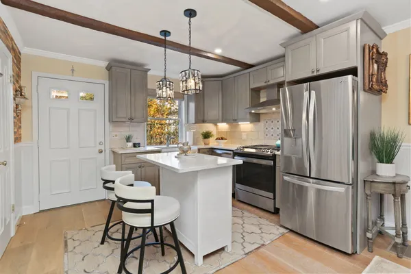 a kitchen with stainless steel appliances granite countertop a refrigerator a sink dishwasher a stove and white cabinets