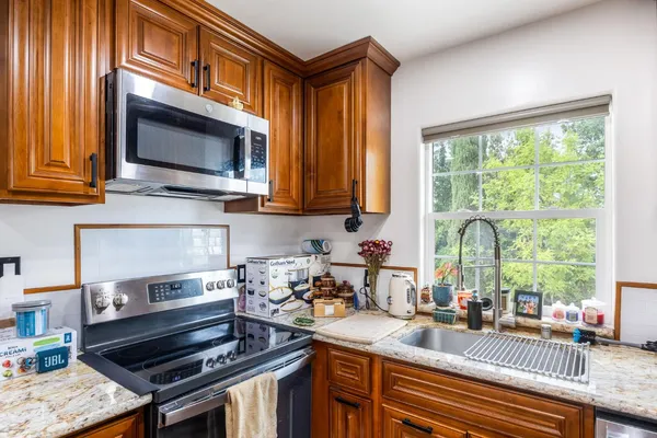a kitchen with stainless steel appliances granite countertop a refrigerator a stove top oven a sink dishwasher and wooden cabinets with wooden floor