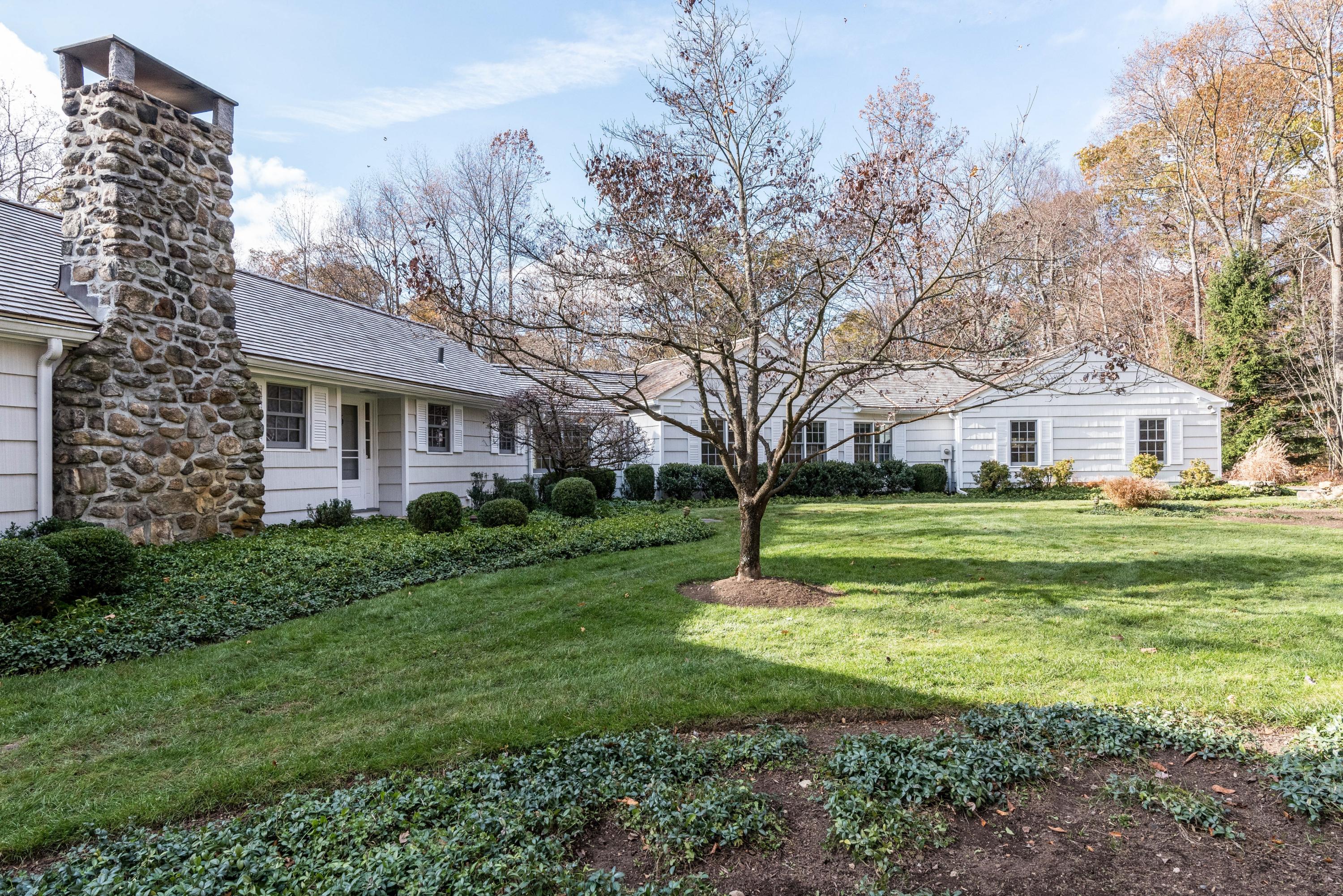 a view of a house with a big yard and large trees