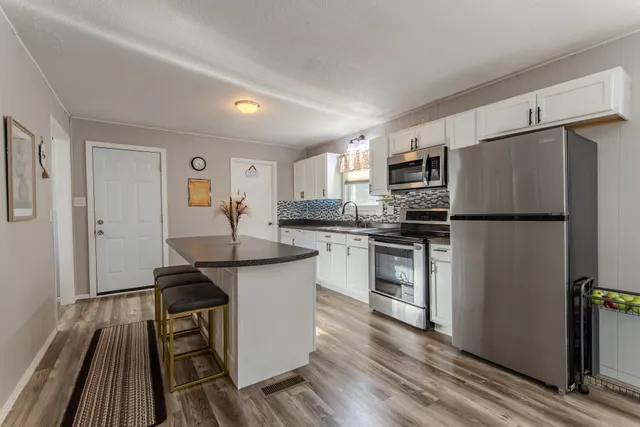 a kitchen with granite countertop a refrigerator stove and sink