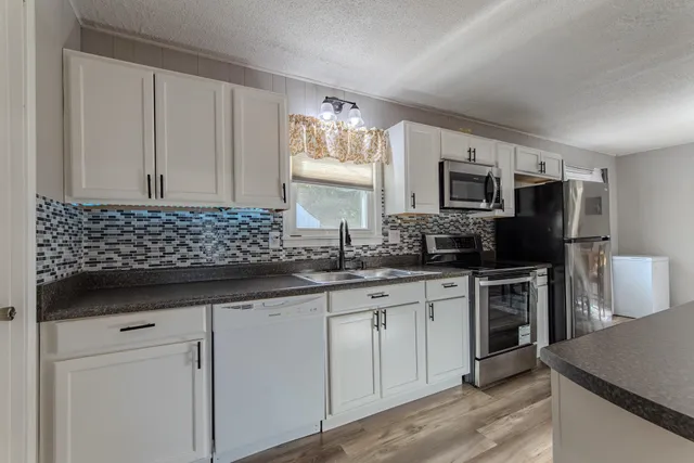 a kitchen with sink a microwave a stove and cabinets