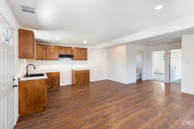a view of kitchen with stainless steel appliances granite countertop a stove top oven a sink dishwasher and a refrigerator with wooden floor