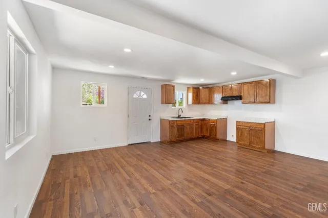 a view of kitchen with stainless steel appliances granite countertop a stove top oven a sink dishwasher and a microwave with wooden floor
