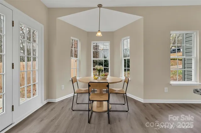 a dining room with wooden floor a chandelier a wooden table and chairs