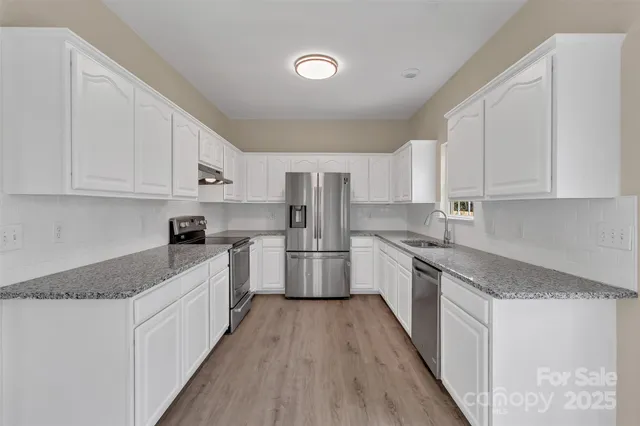 a kitchen with stainless steel appliances granite countertop a stove a sink and white cabinets