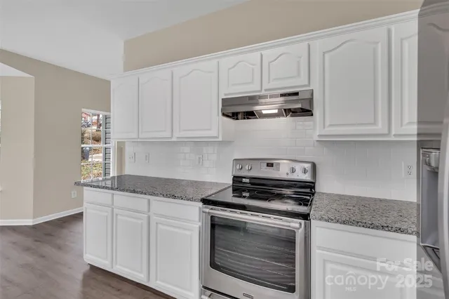 a kitchen with stainless steel appliances granite countertop white cabinets and a stove a sink with dishwasher