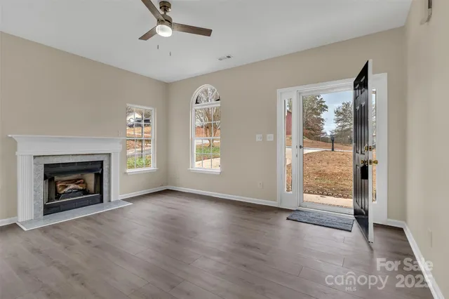 an empty room with wooden floor fireplace and windows