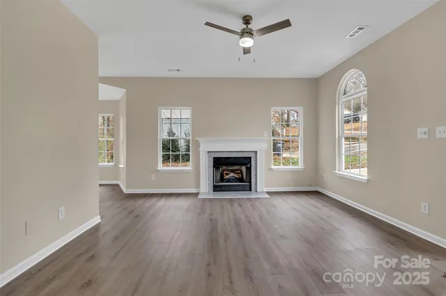 an empty room with windows a fireplace and wooden floor