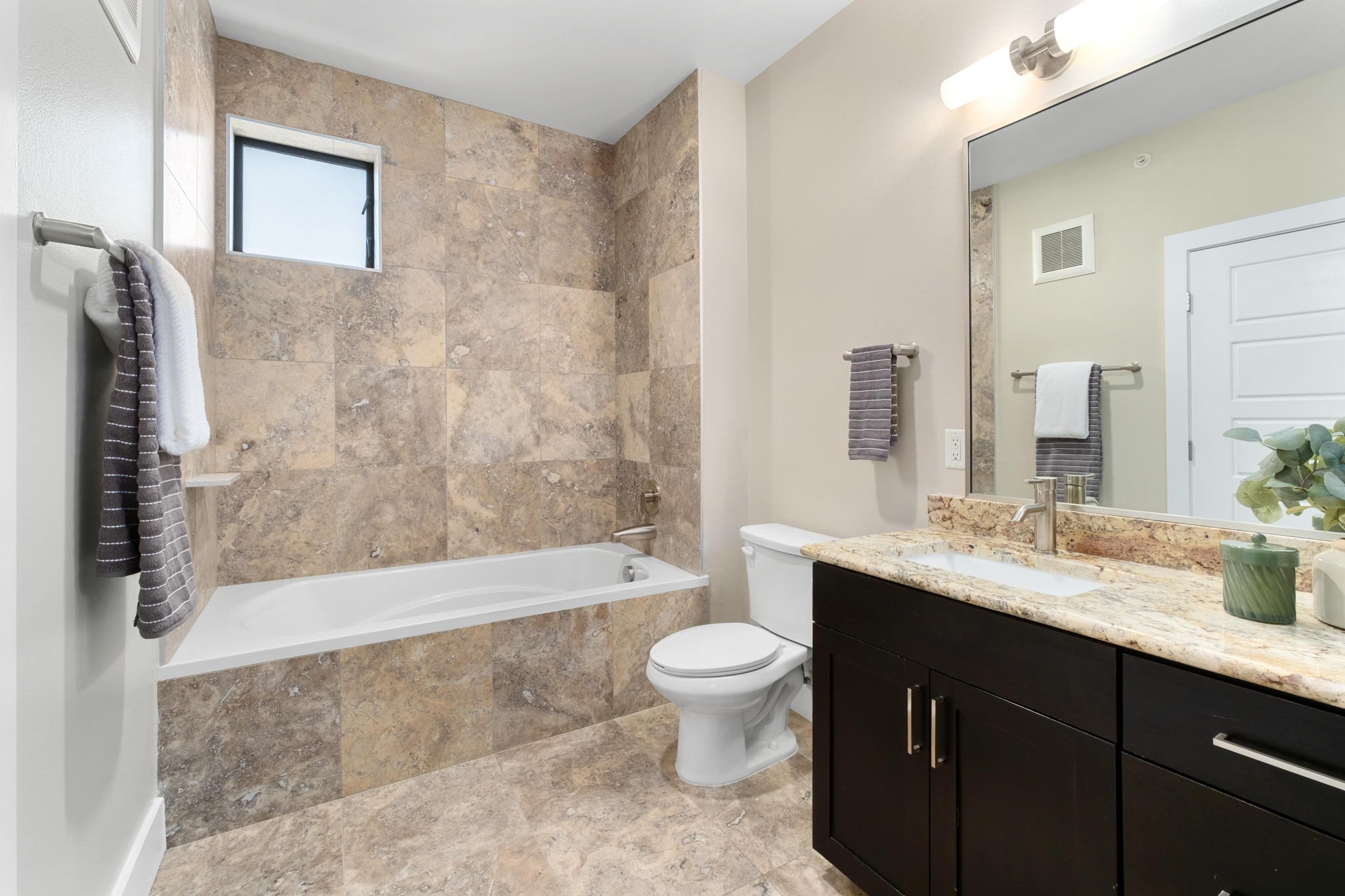 1615 East 7th Street, Unit 402 Austin, TX 78702 - Photo 12 of 23 a bathroom with a granite countertop sink a toilet a mirror a bathtub and shower