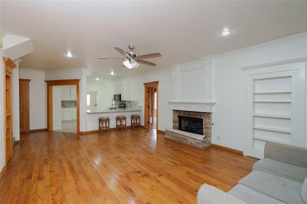 364 Parker Road, Unit A Van Alstyne, TX 75495 - Photo 10 of 39 Spacious living area is open to the kitchen and bar area, featuring wood-finish flooring, a stone-surround fireplace with mantel, and built-in shelving
