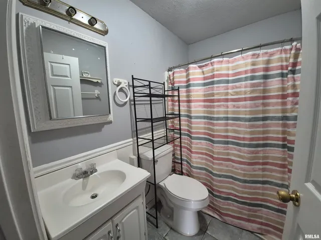 a bathroom with a sink a toilet and shower curtain