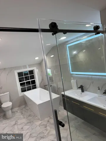 a bathroom with a sink a toilet a mirror and shower
