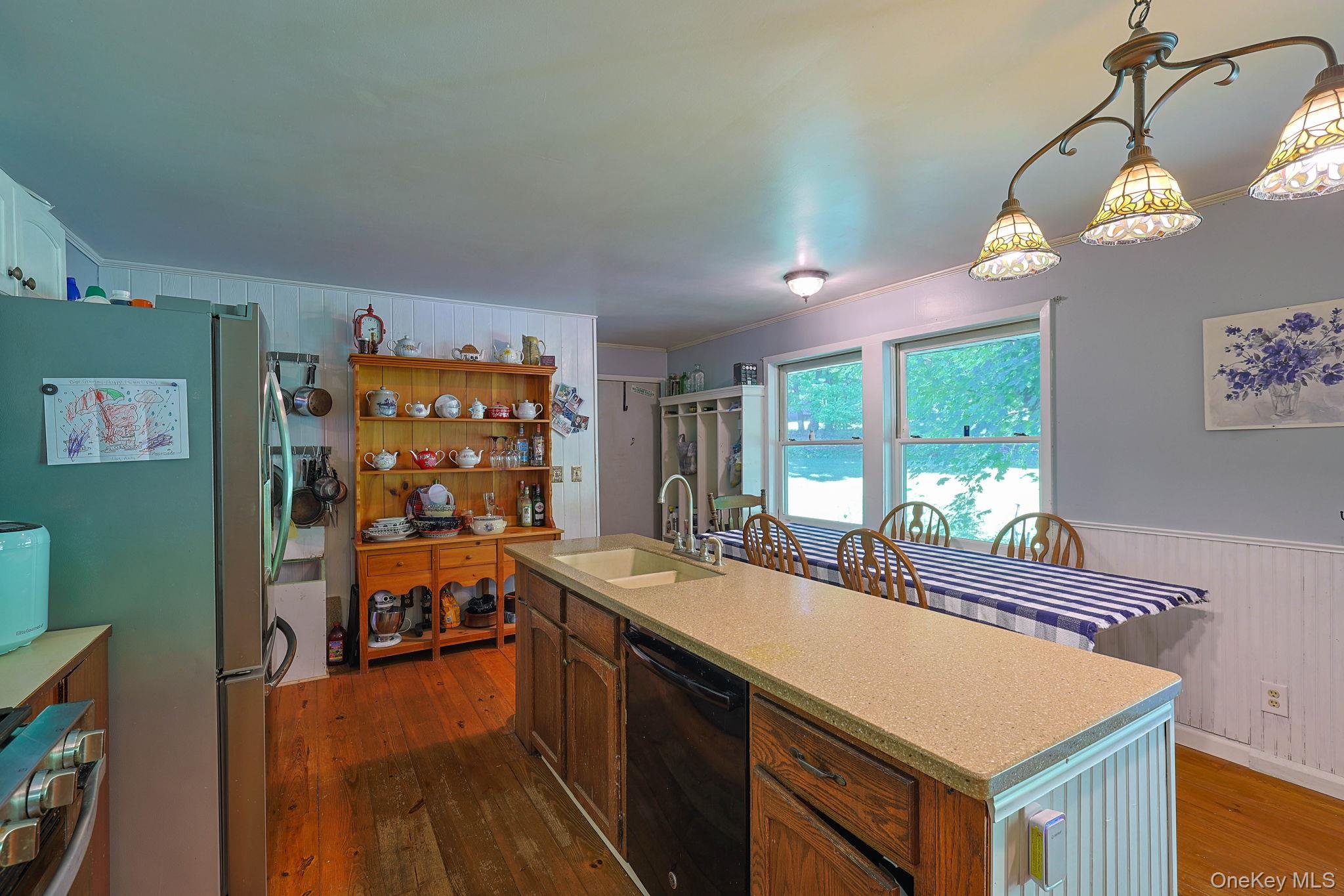 646 County Rte 93 Slate Hill, NY 10973 - Photo 7 of 21 Kitchen featuring wood-finish flooring, a central island with a double basin sink and integrated dishwasher, and a dining area with multiple windows