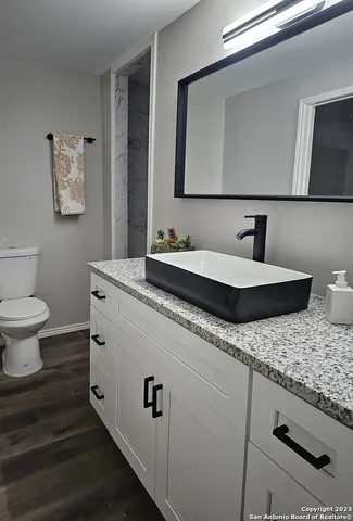 a bathroom with a granite countertop toilet sink and mirror