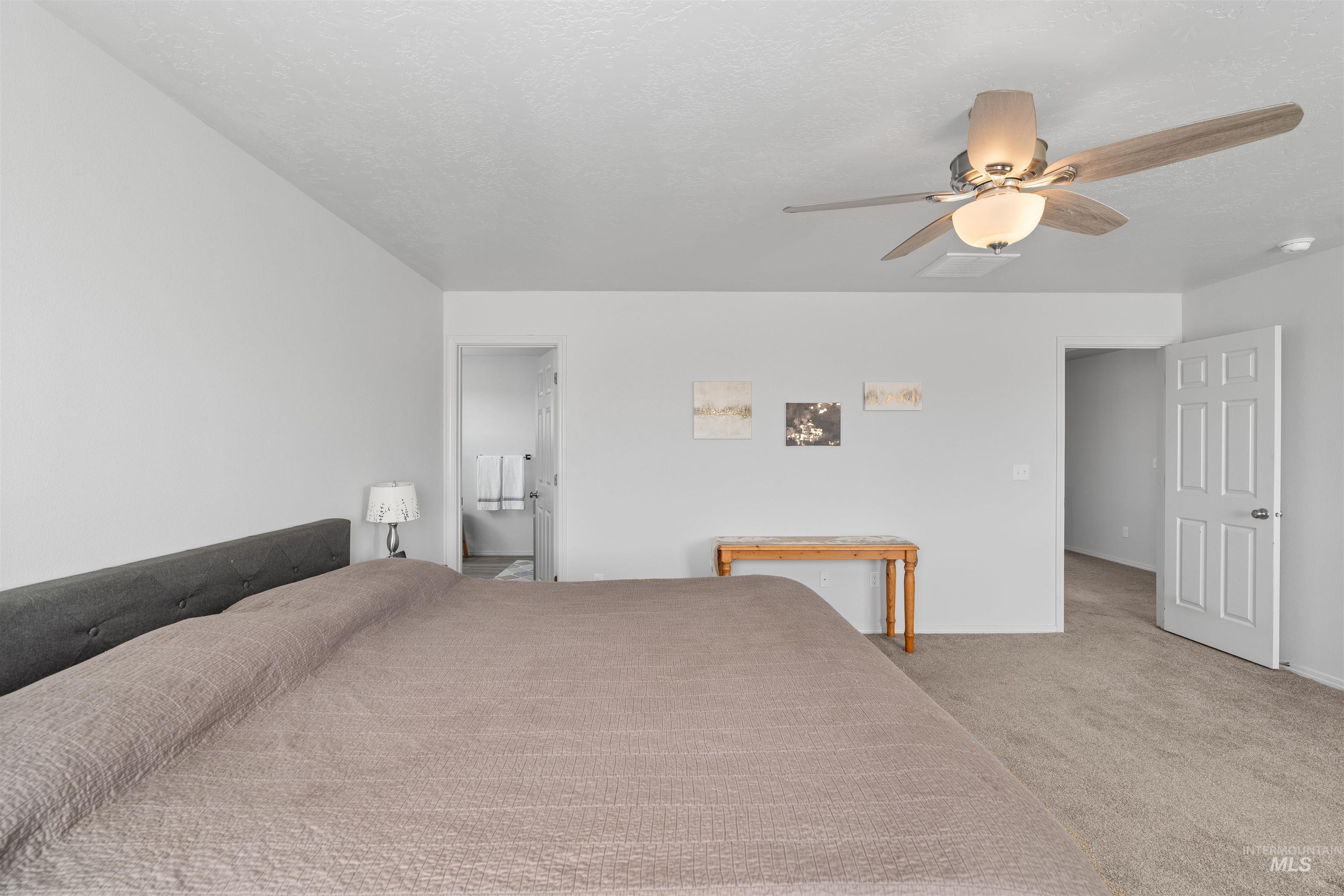 12731 Sondra Street Caldwell, ID 83607 - Photo 21 of 46 Bedroom featuring light carpet, a ceiling fan, ensuite bathroom, and a textured ceiling