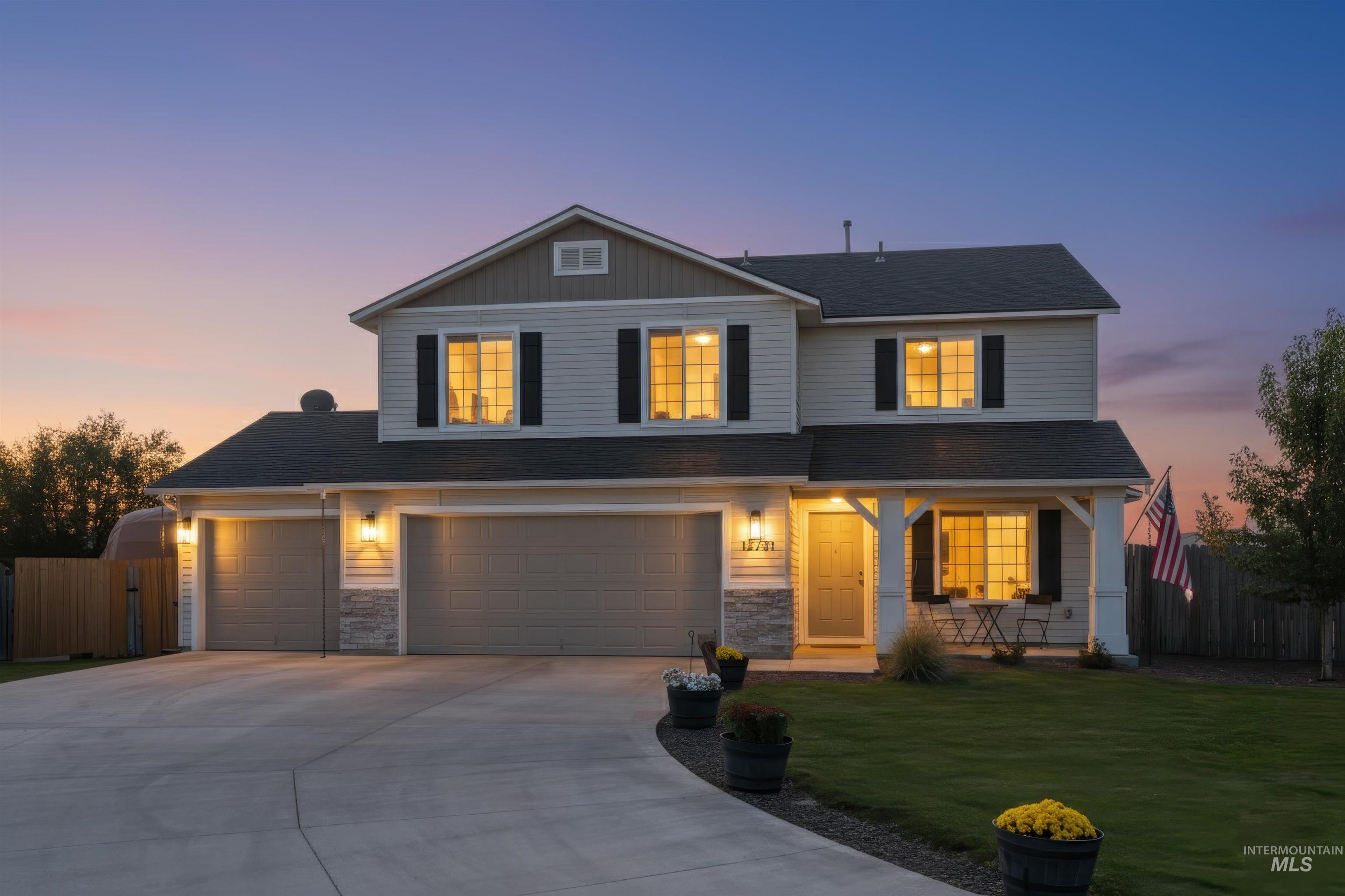 12731 Sondra Street Caldwell, ID 83607 - Photo 43 of 46 Traditional-style house featuring driveway, a porch, an attached garage, and a shingled roof. Virtual twilight.