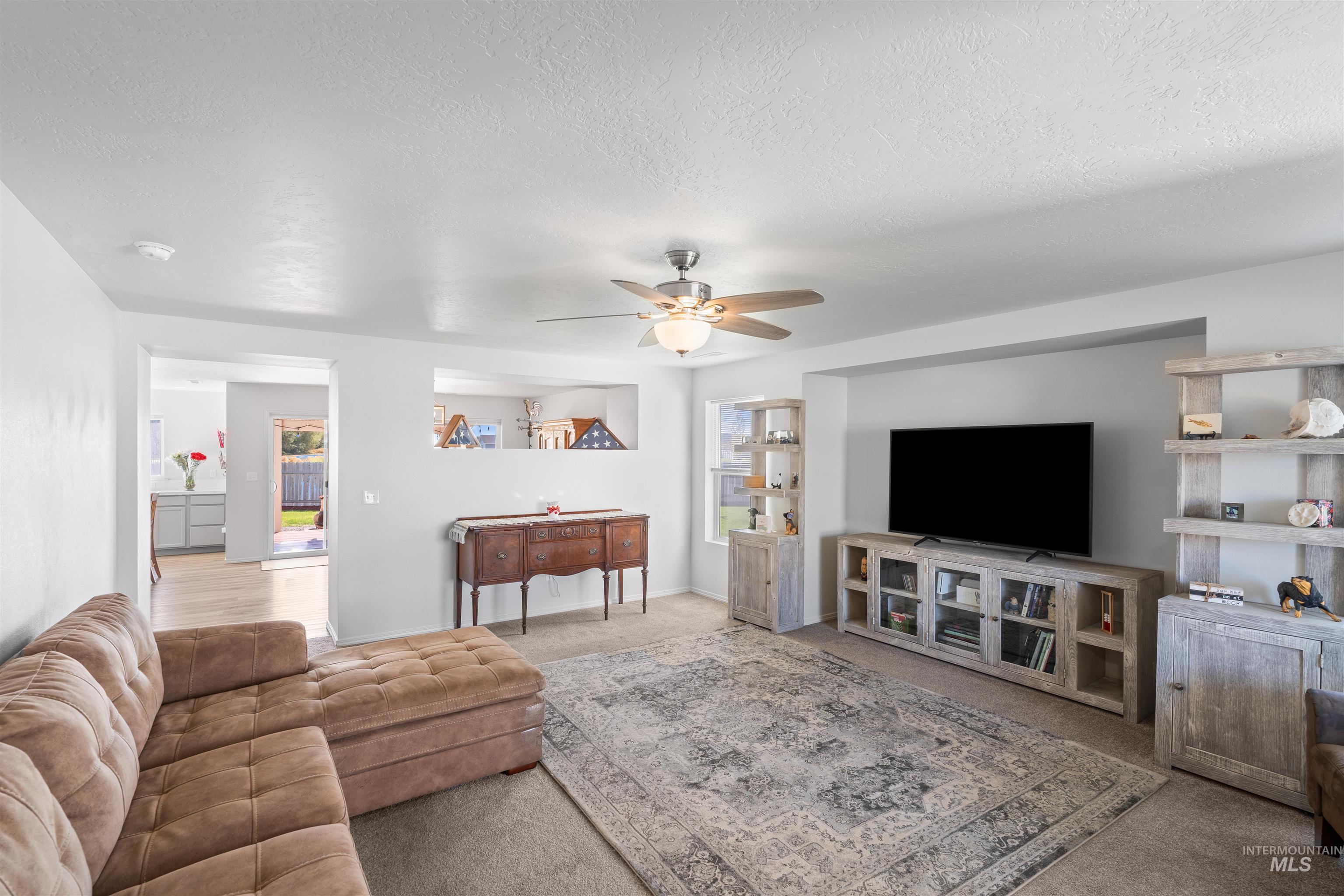 12731 Sondra Street Caldwell, ID 83607 - Photo 7 of 46 Living room with carpet, ceiling fan, and a textured ceiling