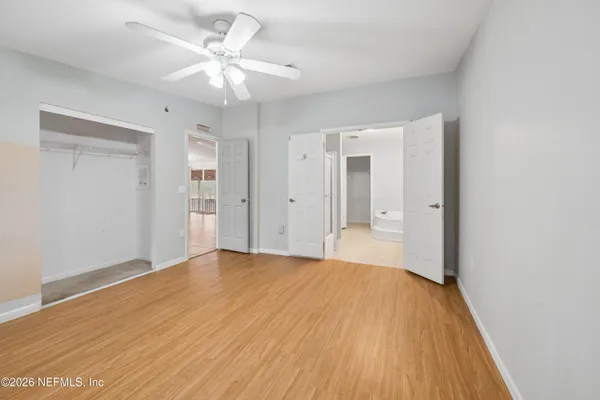 a view of a big room with wooden floor and a chandelier fan