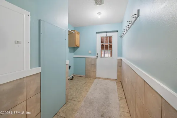 a view of a kitchen with white cabinets and window