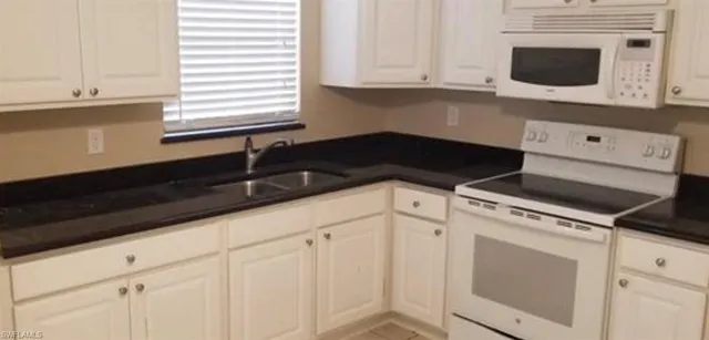 a kitchen with white cabinets and black appliances