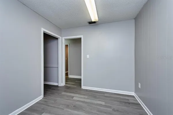 a view of an empty room with wooden floor and closet