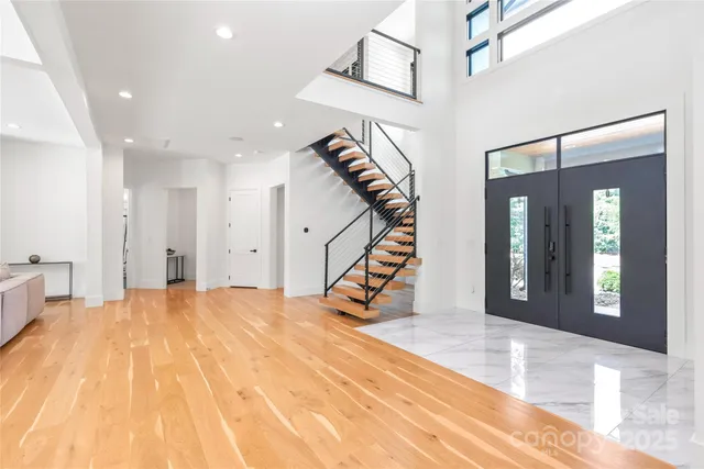 a view of an empty room with stairs and wooden floor