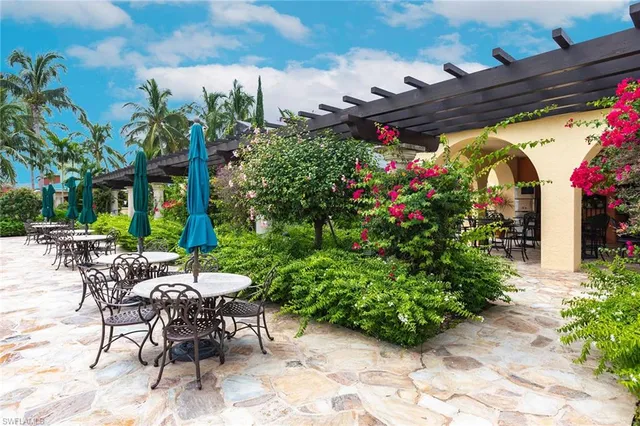 a view of a patio with table and chairs potted plants and large tree