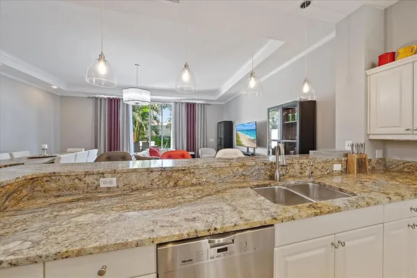 a kitchen with granite countertop a sink white cabinets and chairs
