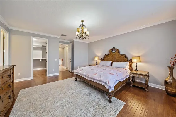a bedroom with a bed and a lamp on table with wooden floor