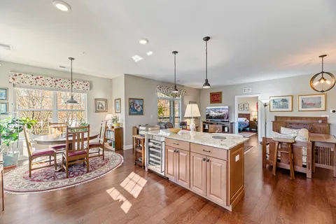 a room with stainless steel appliances kitchen island granite countertop a table chairs and a stove