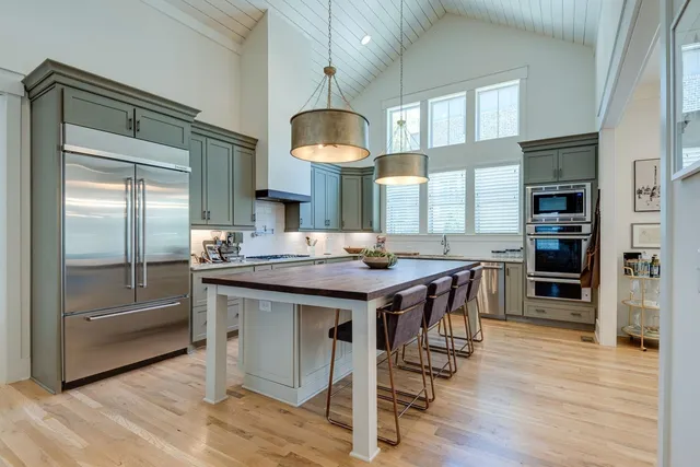 a kitchen with stainless steel appliances granite countertop a table chairs and a refrigerator