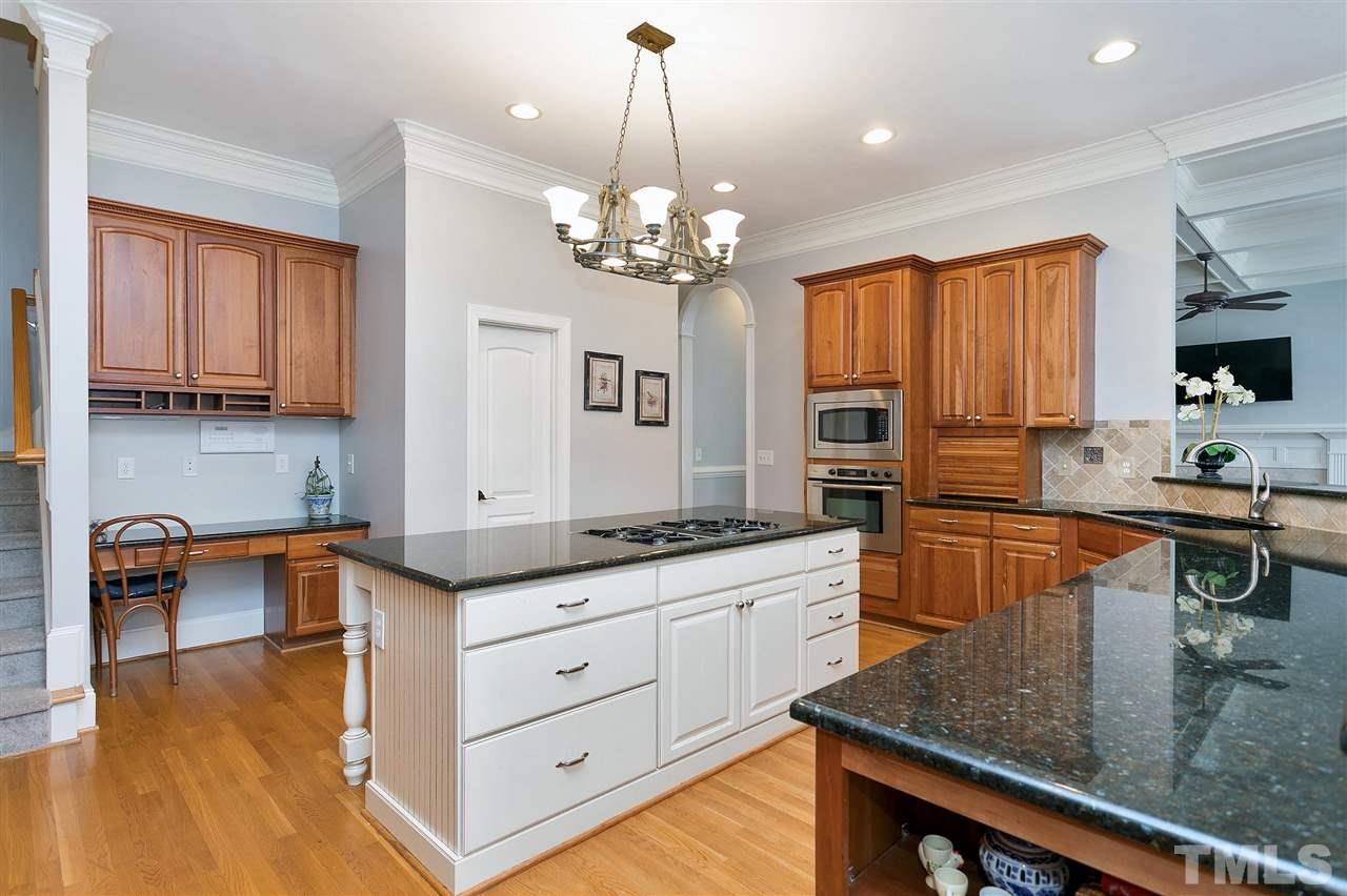 2521 Hunters Meadow Lane Raleigh, NC 27606 - Photo 14 of 30 a kitchen with granite countertop a stove a sink a dining table and chairs