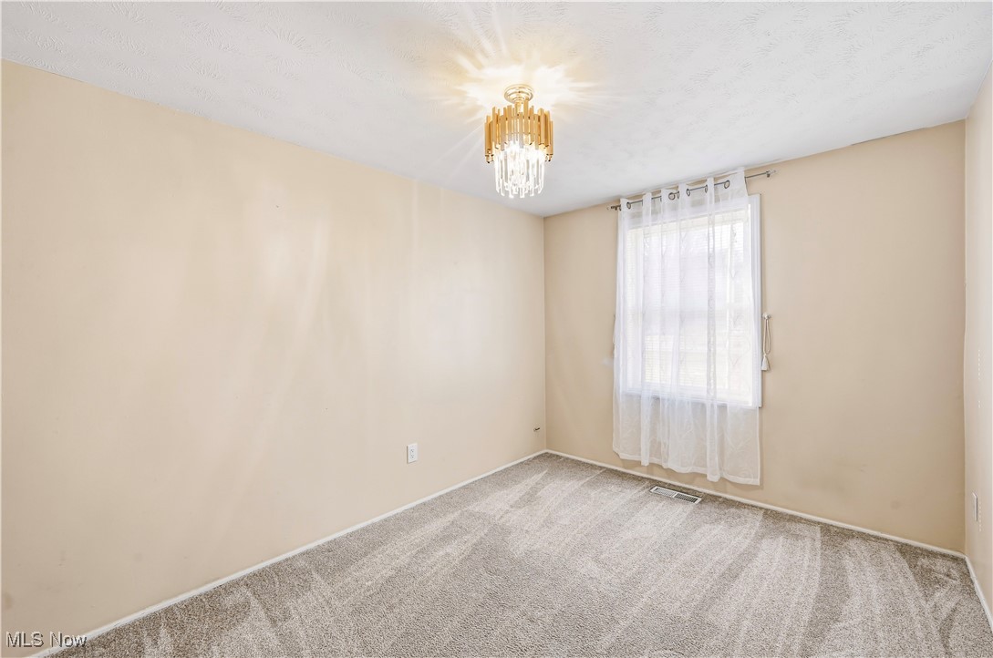 245 North Road Niles, OH 44446 - Photo 32 of 45 Empty room with carpet floors, a chandelier, and a textured ceiling