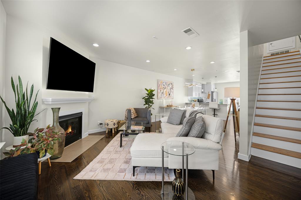 3922 Gilbert Avenue, Unit 214 Dallas, TX 75219 - Photo 10 of 27 Spacious living area featuring dark wood-finish flooring, a white mantel fireplace, and recessed lighting