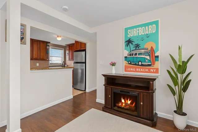 a living room with stainless steel appliances furniture a fireplace and a window