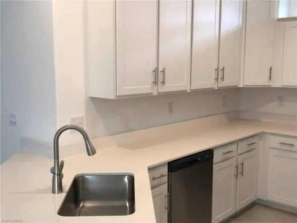 a kitchen with granite countertop white cabinets and a sink