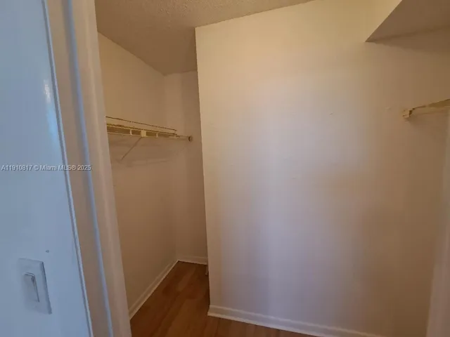 an empty room with wooden floor chandelier and windows